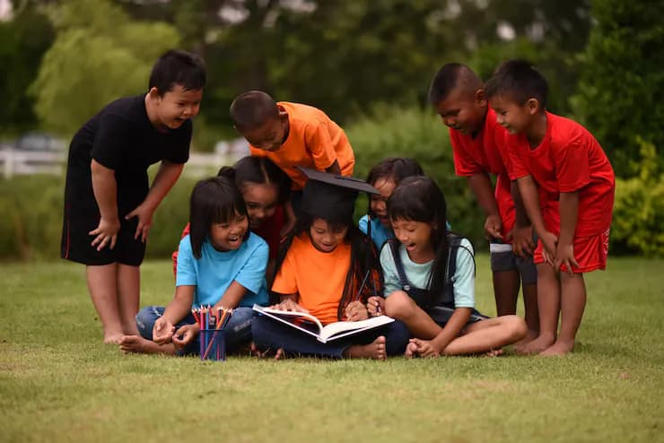 Children lying on the grass reading a book together