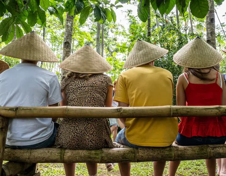 Farmers in conical hats resting on a bamboo bench
