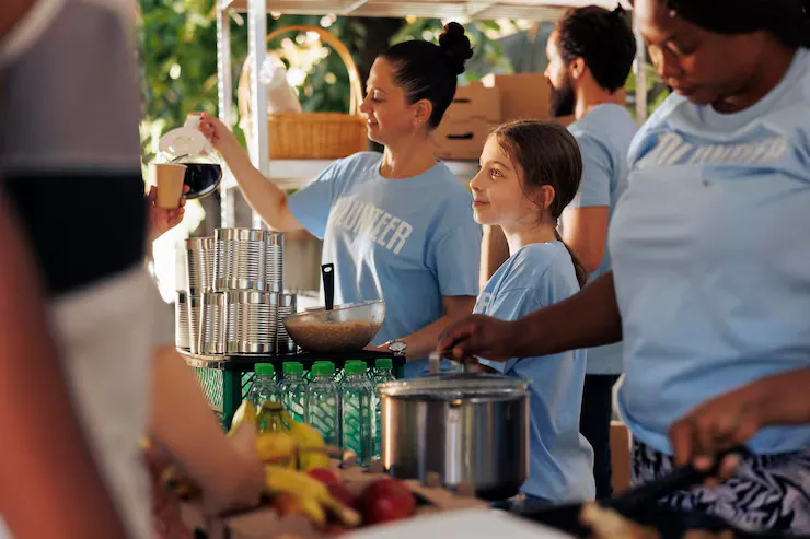 Volunteers serving food from urns at a community kitchen