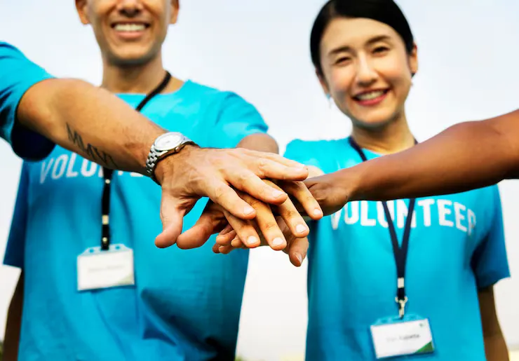 Volunteers in matching shirts stacking their hands together